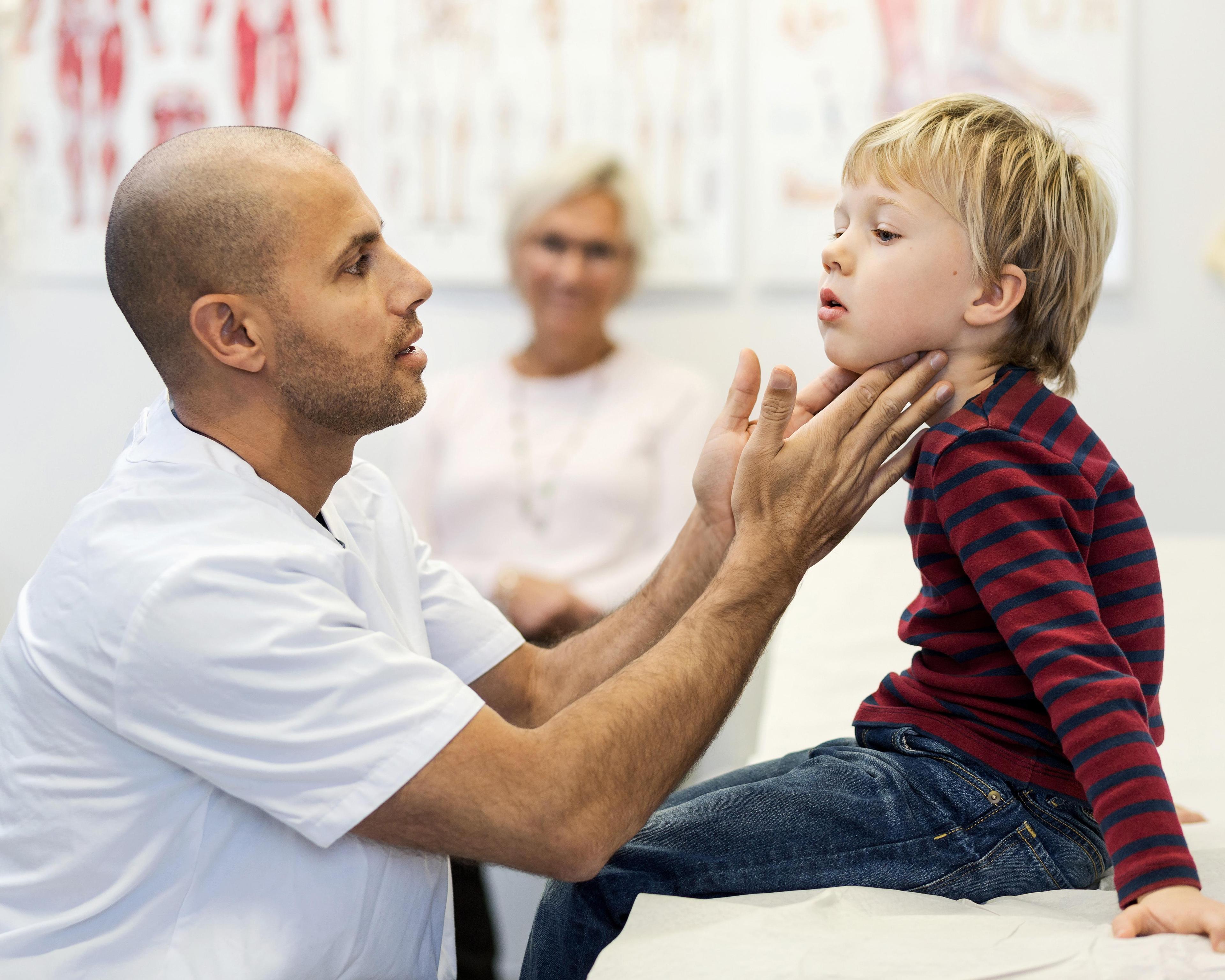 Male doctor checking boys throat at clinic 551423613.jpg